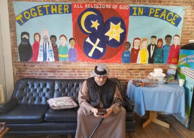 A man sits infront of a banner with various symbols and words together in peace
