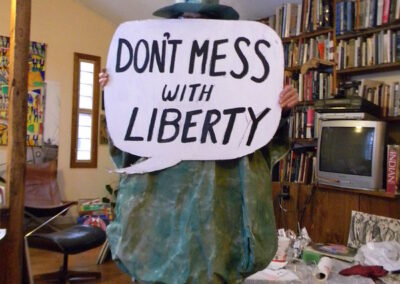 Figure wearing oversized Liberty costume holds sign, "Don't mess with Liberty"