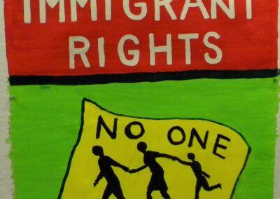 a red and green banner with "We demand Immigrant rights - no one is illeagal"