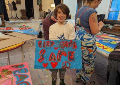 smiling child proudly holds sign created at ARRT workshop