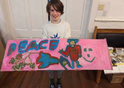 Child smiling holds the sign they made with Peace and happy pictures